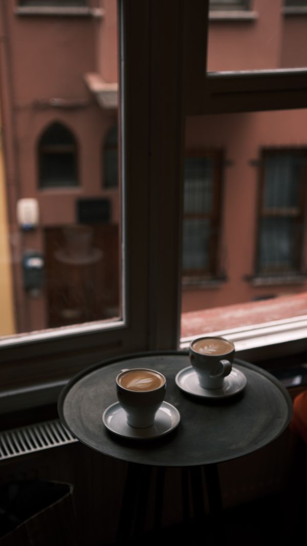 Deux tasses de café sur un plateau près d'une fenêtre