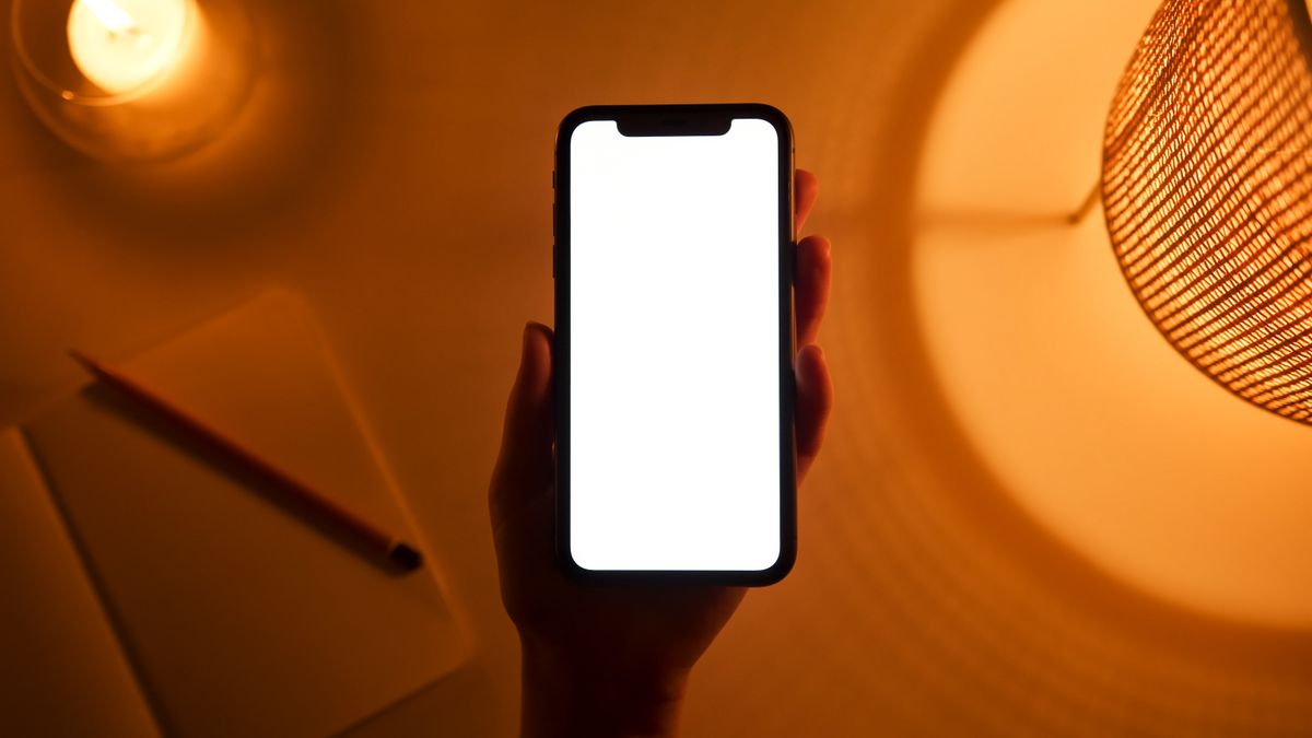 Une main tient un téléphone dans une lumière chaude